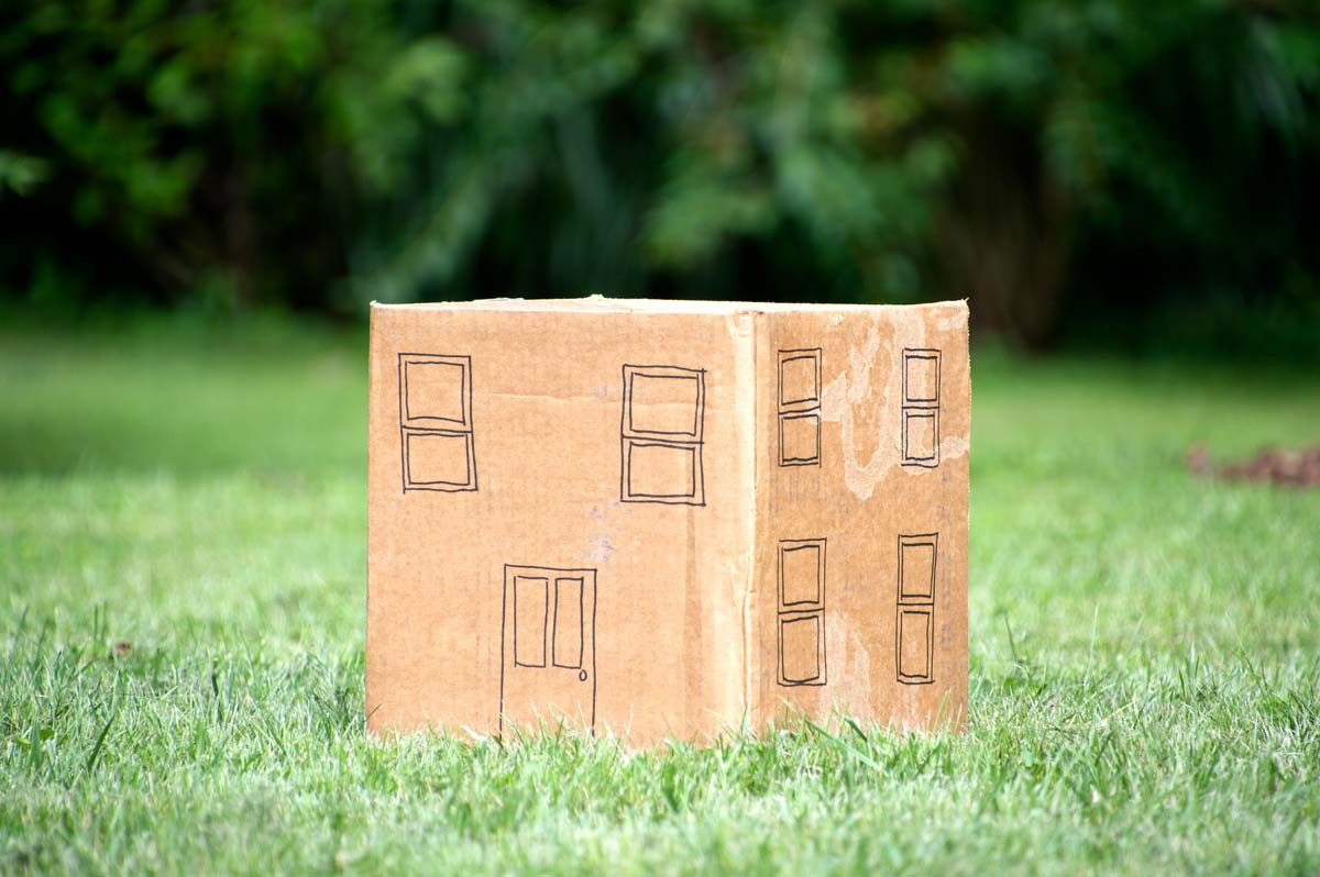 Model house made out of a cardboard box with the top flaps closed, illustrating that air leakage is still a concern relative to conductive heat loss.