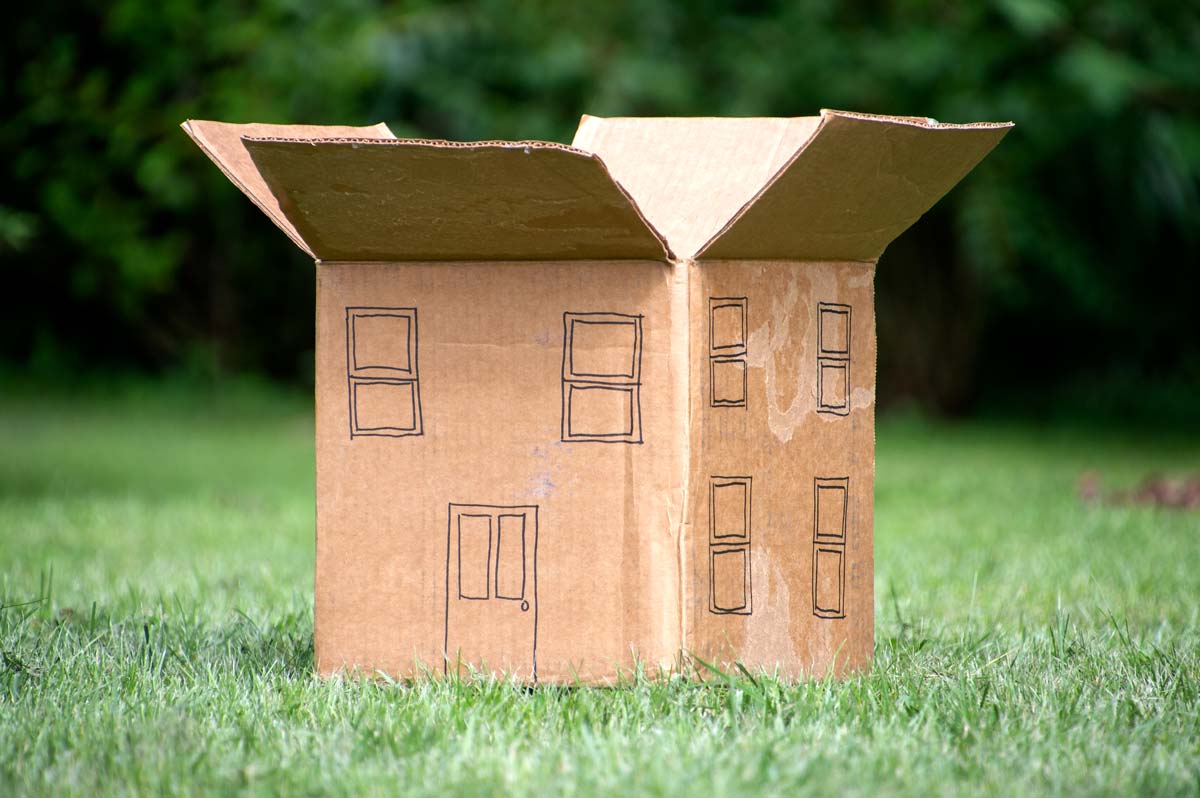 Model house made out of a cardboard box with the top flaps wide open, illustrating an extreme case where air leakage is obviously more important than conductive heat loss.