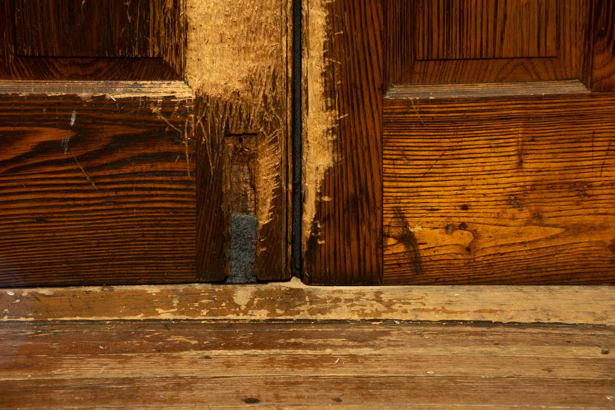 Close-up image of a door with felt weatherstripping plugging a hole where a flush bolt should be.