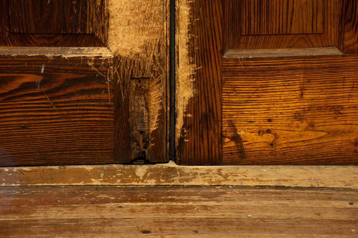 Close-up image of a door with a hole where a flush bolt is missing.