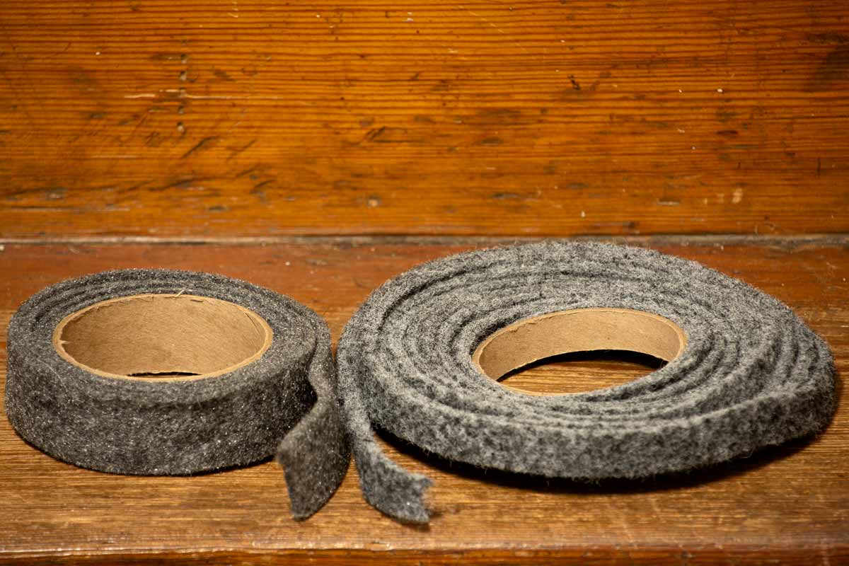 Two rolls of different-sized felt weatherstripping on a wood shelf.