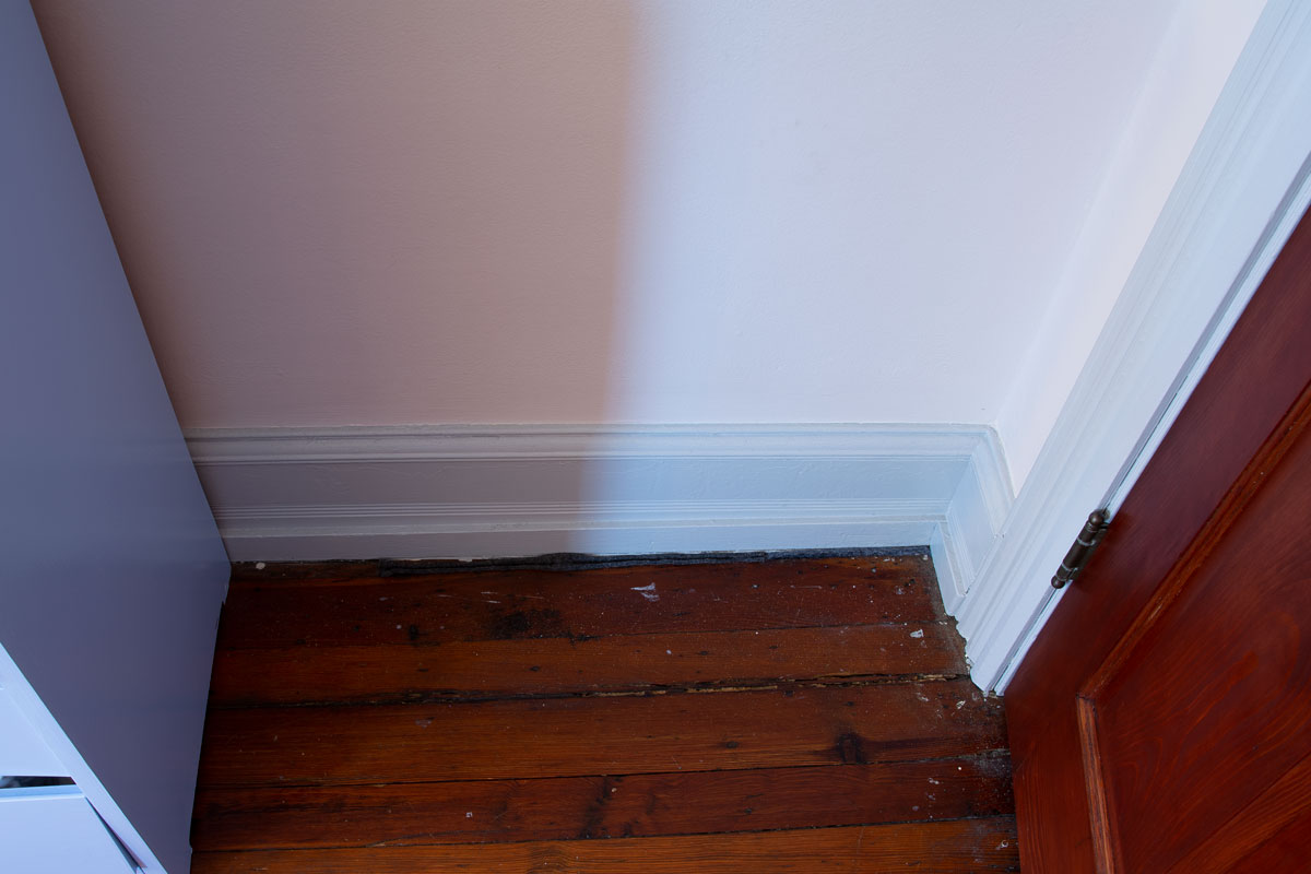 Felt weatherstripping in gap between floorboards, viewed from a distance.