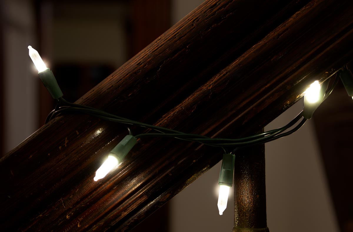 Close-up of white LED Christmas lights wrapped around a dark wood bannister.