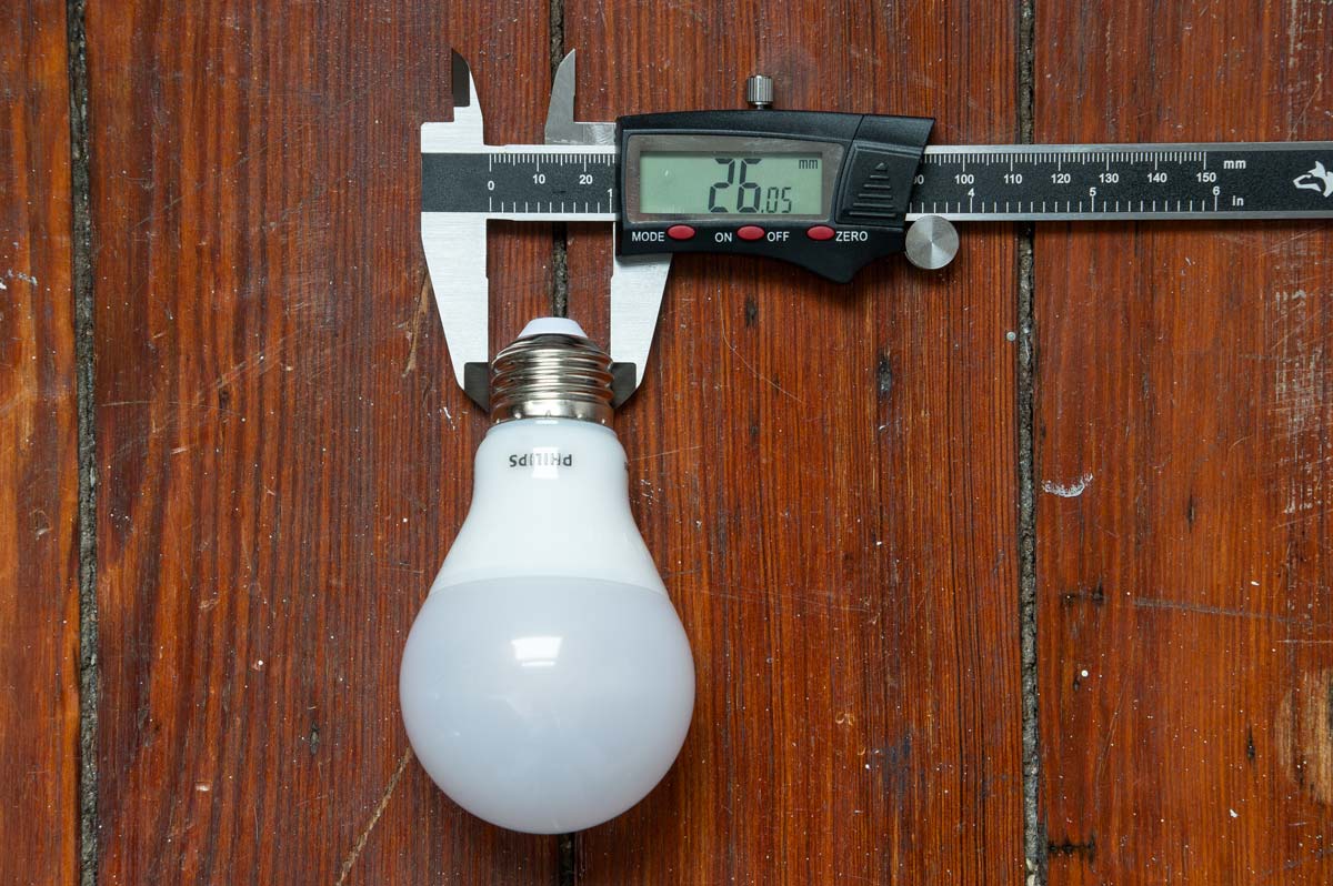 LED light bulb with a digital caliper showing the width of an E26 base.