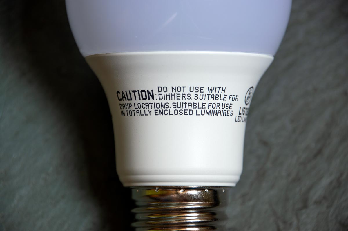 Close-up of an LED bulb showing label: Do not use with dimmers. Suitable for damp locations. Suitable for use in totally enclosed luminaires.